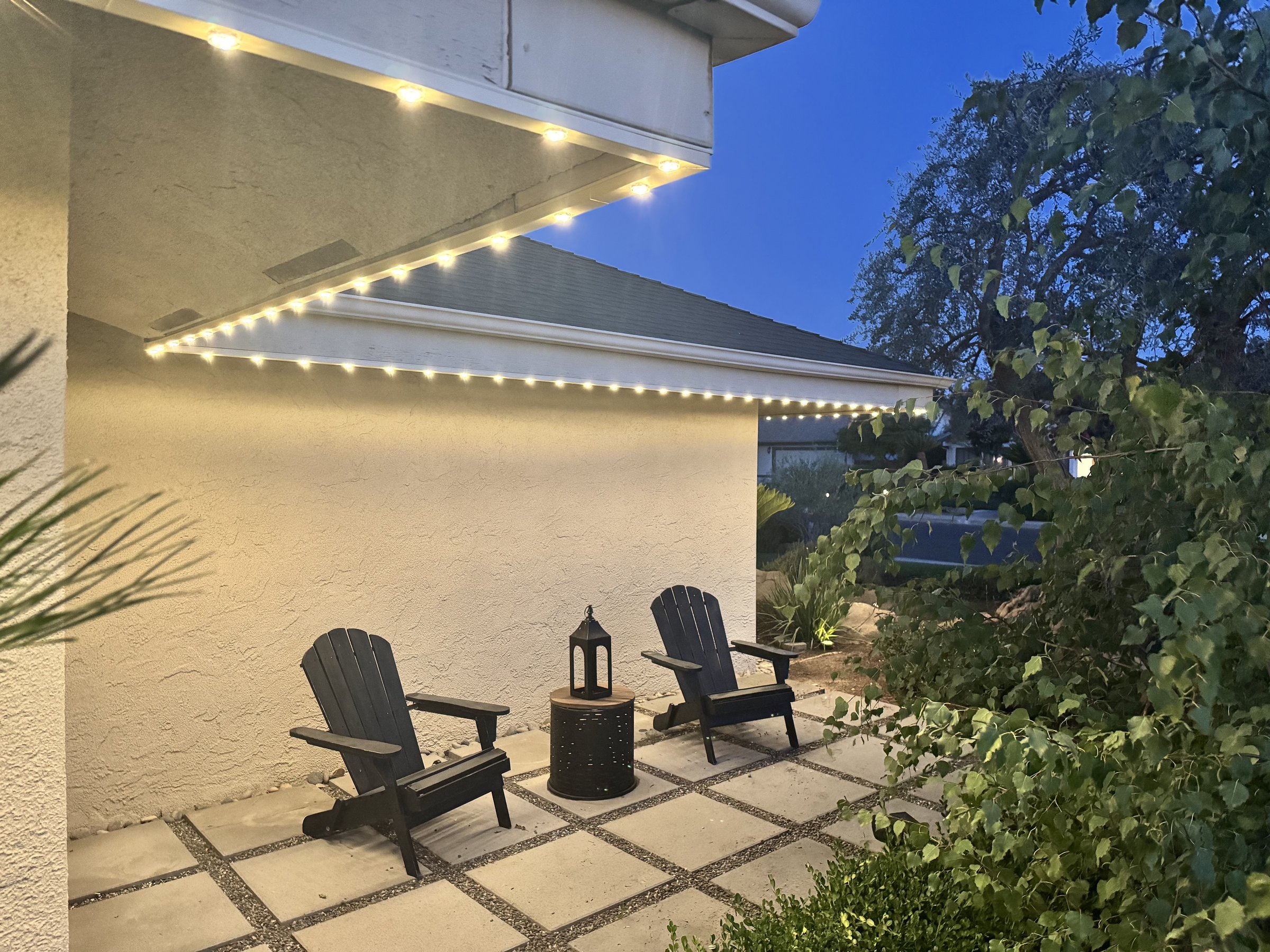 Patio seating area under EverLume roofline lighting at dusk