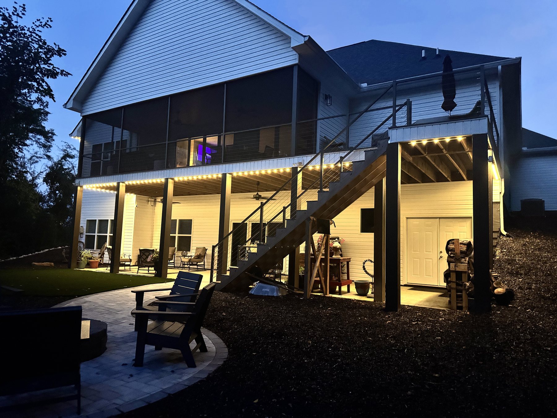 EverLume permanent lighting along a two-story home's covered patio at dusk